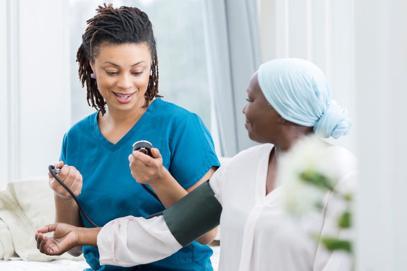 Riverview Hospice and Palliative Care LLC | Nurse taking blood pressure of a patient with a stethoscope in the patient's home